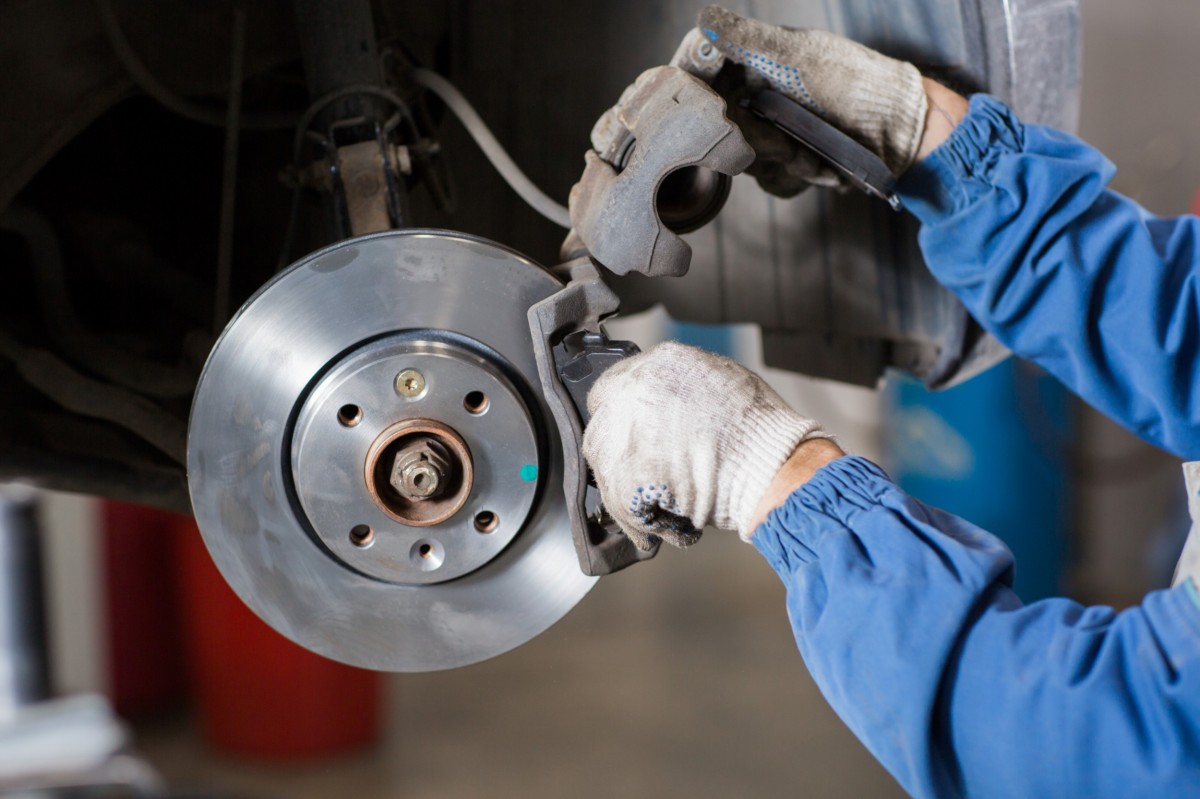 mechanic working on brakes on car on lift