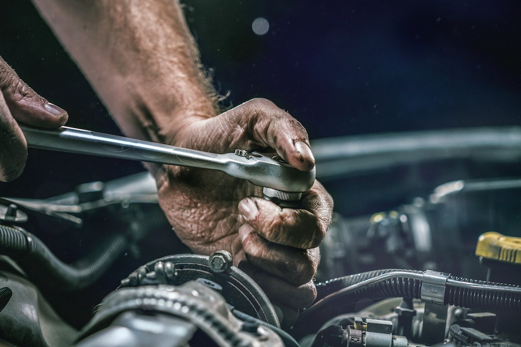 mechanic turning wrench on a car